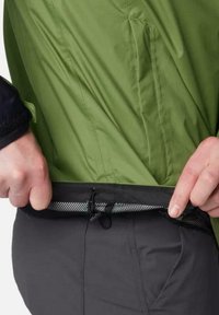 Schwarze Outdoor-Hosen mit elastischem Bund und Mesh-Futter, verstellbare Kordelzüge. Im Hintergrund ist eine grüne Jacke sichtbar, die eine glatte Textur aufweist.