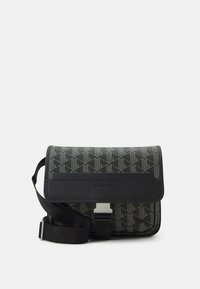 Crna torba na rame s geometrijskim uzorkom, s preklopnim poklopcem, srebrnim detaljima i podesivim remenom. Materijali od kože i tkanine.