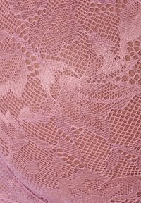 Tessuto di pizzo rosa che presenta motivi floreali con sezioni a rete aperta e una consistenza liscia, mettendo in evidenza dettagli intricati e bordi cuciti.