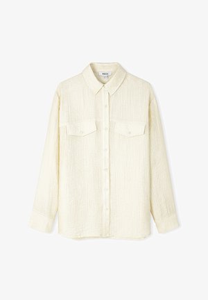 Jasna kremowa koszula z teksturowanej tkaniny, z długimi rękawami, kołnierzykiem w szpic, zapięciem na guziki z przodu oraz dwoma kieszeniami na piersiach.