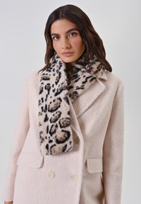 Écharpe en fausse fourrure à imprimé léopard avec une texture douce, associée à un manteau rose clair texturé d'un design à double boutonnage et de grands boutons.
