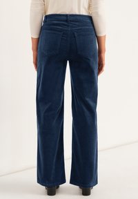 Wide-leg corduroy pants in deep navy blue, featuring rear pockets, a textured fabric, and a high waist design.