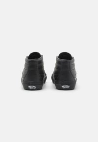 Sneaker alte nere in pelle, con superficie texturizzata, collo imbottito e logo Vans sulla suola in gomma.