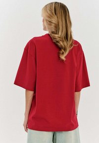 Czerwona, duża koszulka z krótkim rękawem, wykonana z miękkiej bawełny. Posiada luźny krój i prosty design bez wzorów.