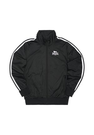 Chaqueta deportiva negra con cierre de cremallera, cuello alto, rayas laterales blancas, dos bolsillos con cremallera y logo bordado en el pecho. Tejido suave y liso.