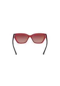 Gafas de sol de gradiente rojo con forma de ojo de gato, que presentan montura transparente roja y varillas negras con un sutil acento rosa en el interior.