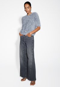 Light blue fluffy short-sleeve sweater paired with wide-leg dark gray jeans. The outfit is complemented by simple strappy sandals.