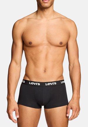 Muscular male torso wearing black Levi’s branded boxer briefs, standing against a plain light background.
