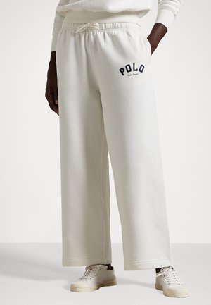 Light beige sweatpants with a relaxed fit, featuring a drawstring waist and "POLO" logo in navy. Soft, textured fabric with pockets.