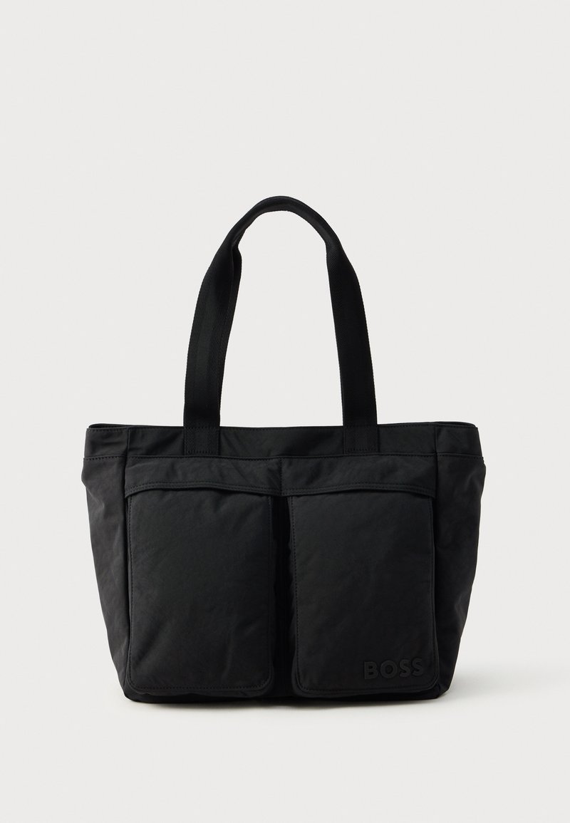 Sac fourre-tout noir en tissu doux, avec deux poches avant et des anses robustes. Logo affiché sur le côté. Design simple et fonctionnel.