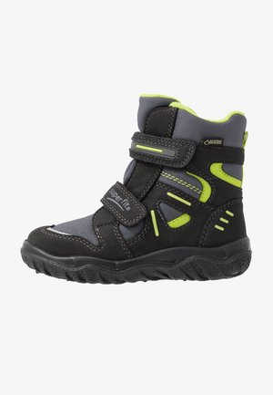 Schwarze und graue Winterstiefel mit strukturiertem Finish, ausgestattet mit neon-grünen Akzenten, verstellbaren Riemen und einer robusten Sohle für gute Traktion.