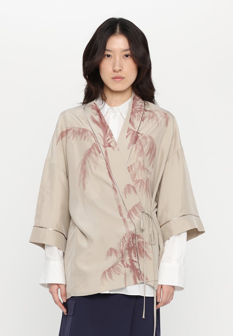 Beige spalvotu kimono stiliaus švarkas su dulkių rožinės spalvos palmės lapų printu. Plačios rankovės ir surišamas užsegimas. Subtilūs metaliniai akcentai.