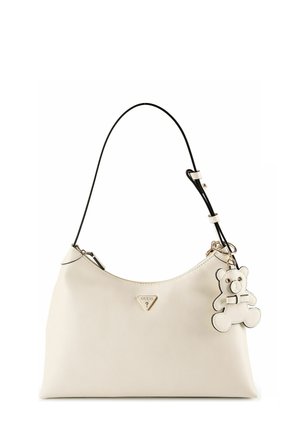 Sac à main en cuir crème avec bandoulière noire, logo Guess triangulaire et porte-clés peluche crème attaché.