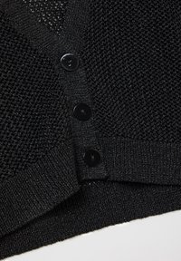 Cárdigan de punto negro con un patrón texturizado, escote en V y cinco botones negros brillantes en la parte delantera. Material suave y ligero.