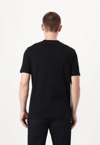 Svart kortermet T-skjorte med klassisk rund hals. Mykt stoff, minimalistisk design, med en subtil logodetalj på baksiden.