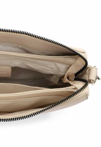 Torba z brązowej skóry z czarnym zamkiem błyskawicznym, z jedną główną przegrodą i dwoma wewnętrznymi kieszeniami, gładką fakturą i prostymi liniami.