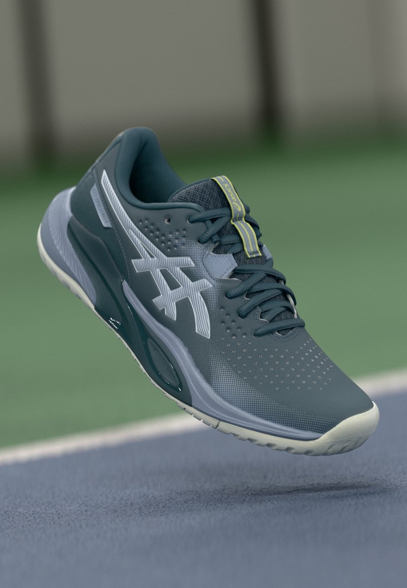 Sportssko i mørkeblå med lys blå accent, mesh-overdel, perforeret tekstur, snørebånd og logo på siden. Hvid gummisål.