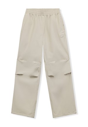 Pantalon beige à jambes larges avec taille élastique et poche latérale, avec un petit patch rectangulaire sur la partie supérieure de la cuisse.