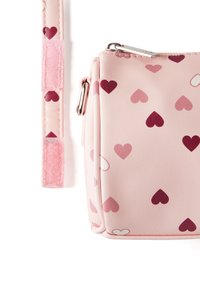 Růžová crossbody taška s texturovaným povrchem, zdobená náhodně rozmístěnými srdíčky v tmavě červené a světle růžové barvě. Obsahuje odpovídající popruh.