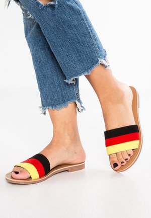 Sandaler med åbent tåspids og flad sål. Remmene har vandrette striber i rød, sort og gul. Materialet virker blødt og tekstureret.