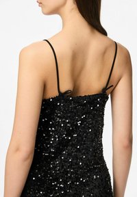 Crna haljina sa šljokicama i trakama preko ramena, koja ima prilagođeni siluet i teksturiranu površinu sjajnih šljokica za reflektirajući efekt.