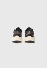 Baskets de sport noires et beiges avec une semelle extérieure texturée, un design élégant et un dessus en tissu lisse avec des rayures colorées.