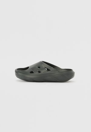 Donkergroene instapklomp gemaakt van een rubberachtige materiaal, met uitsparingen voor ventilatie en een gestructureerde voetbed voor comfort.