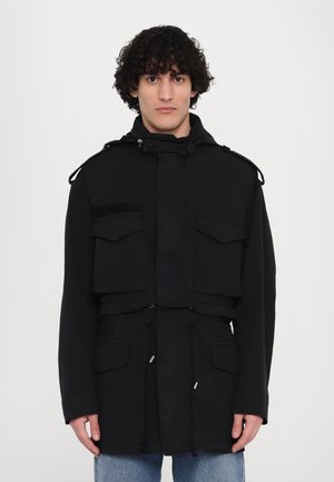 Must-haves mustarjää kinnaste kabrak, kus kõrgema kraega ja esiväikeste taskutega, jooned alati ihurihmaga ja nööbid õlgadel. Kangas tundub tugev ja tekstureeritud.