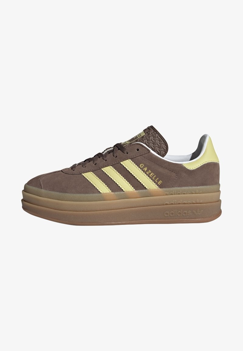 Brown Adidas Gazelle sneaker with yellow stripes, thick layered gum sole, and white interior lining, side view.