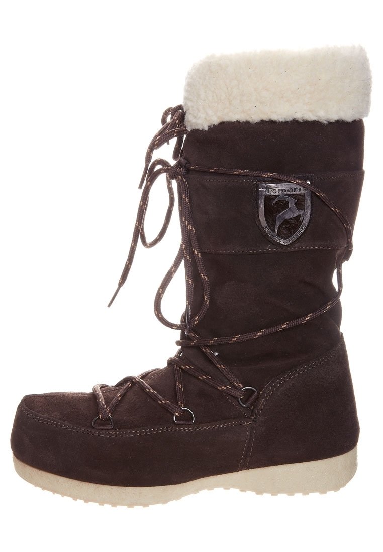 Bota de ante marrón con forro de piel, punta redonda, diseño de cordones texturizados y parche con el logo. Presenta una suela de goma gruesa y de color claro.