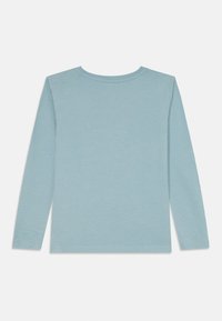 Pitkähihaisen vaatimattoman sinisen paidan, joka on valmistettu pehmeästä kankaasta ja jossa on pyöreä kaula-aukko. Täydellinen sileä pinta ja minimalistinen muotoilu, ilman näkyviä kuvioita tai koristeita.