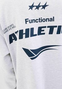 Sudadera atlética de color gris claro con texto en azul marino "ATHLETIC FUNCIONAL" y un diseño gráfico curvado. Textura suave, corte relajado.