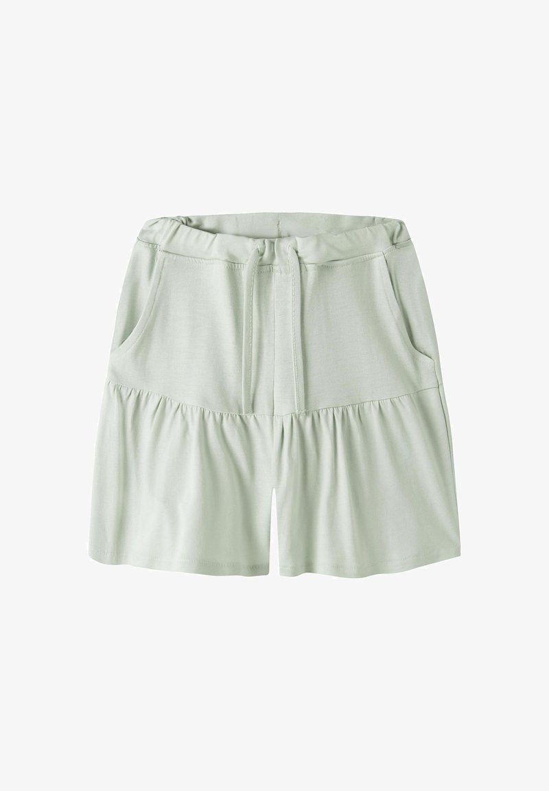 Shorts vert clair à taille élastique avec cordon et poches latérales, avec un détail de couture froncée sous les hanches.
