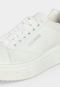 Baskets basses blanches avec lacets blancs et logo "Steve Madden" sur le côté, avec des détails de couture sur la tige.