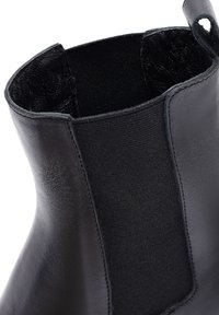 Stivale alla caviglia in pelle nera con pannello laterale elasticizzato e superficie liscia, con punta rotonda e linguetta per una facile calzata.