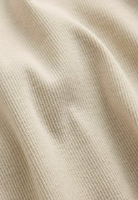 Close-up of beige ribbed fabric showing texture and soft folds.