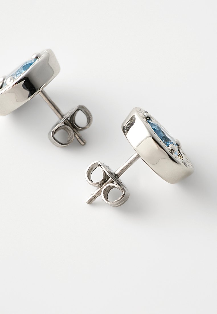 Srebrne kolczyki wkręty z okrągłym wzorem i niebieskim kamieniem w centrum, o gładkiej fakturze i z zapięciem na sztyft.