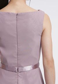 Fialové šaty s kulatým výstřihem na zádech, textura látky je hladká, s saténovým páskem v pase a malým zipem na zádech.