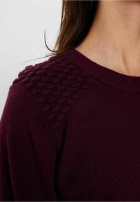 Burgundowy sweter z teksturowanym wzorem dzianiny na ramionach, okrągłym dekoltem i miękkim materiałem.