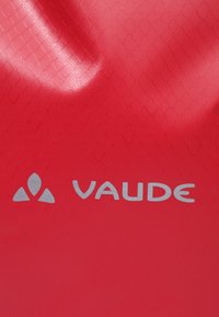 Superficie rossa testurizzata con un sottile motivo a scaglie, con il logo argento "VAUDE" stampato in evidenza.