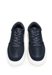 Granatowe skórzane i zamszowe trampki z perforowanymi detalami, płaskimi sznurówkami, wyściełanym kołnierzem i białą gumową podeszwą. Posiadają zaokrąglony czubek.