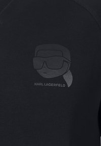 Felpa nera in cotone con una grafica discreta di un personaggio con occhiali da sole e la scritta "KARL LAGERFELD" in grigio chiaro.