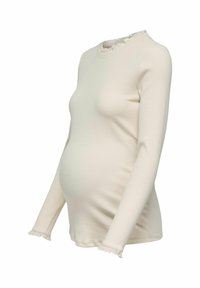 Krämfärgad långärmad gravidtop med ribbad textur, rundad halsringning och volangdekorationer på ärmsluten och kragen. Figurnära design.