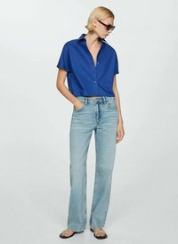 Cropped blue button-up shirt, light wash straight-leg jeans, and black sandals. Smooth fabric, short sleeves, and subtle collar detail.