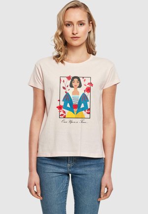 Light pink short-sleeve t-shirt featuring a graphic of a woman with dark hair in colorful attire, surrounded by floral motifs and text below.
