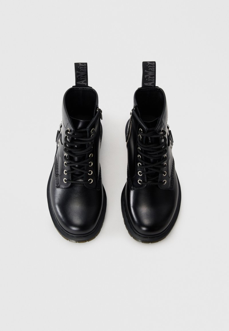 Bottes mi-mollet en cuir noir avec bout rond, laçage à l'avant et œillets en métal. Comprend une fermeture éclair sur le côté et une languette à l'arrière.
