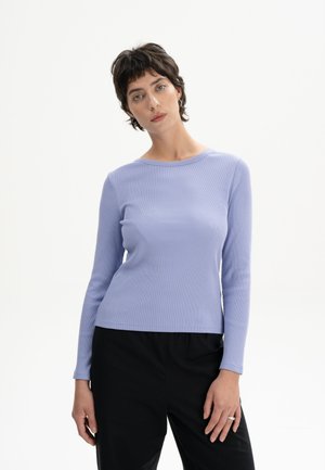 Langärmliges, geripptes, hellviolettes Oberteil mit Rundhalsausschnitt, figurbetonter Form und glatter Textur, kombiniert mit schwarzen, locker sitzenden Hosen.