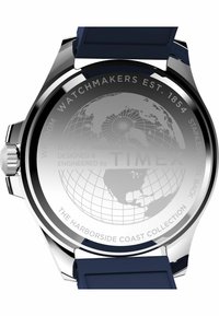 Montre Timex avec un boîtier en acier inoxydable, un bracelet en silicone bleu marine, un design de globe gravé au dos, et un texte détaillant le modèle et la marque.