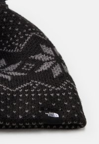 Μαύρο πλεκτό σκουφάκι με γκρίζο γεωμετρικό σχέδιο, διπλωμένη ακμή και μια μικρή ετικέτα με την επωνυμία "The North Face".