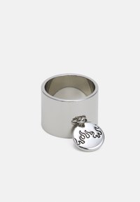 Anel de metal prateado com forma cilíndrica, apresentando um pendente redondo destacável gravado com padrões em forma de chama. Textura suave e brilhante.